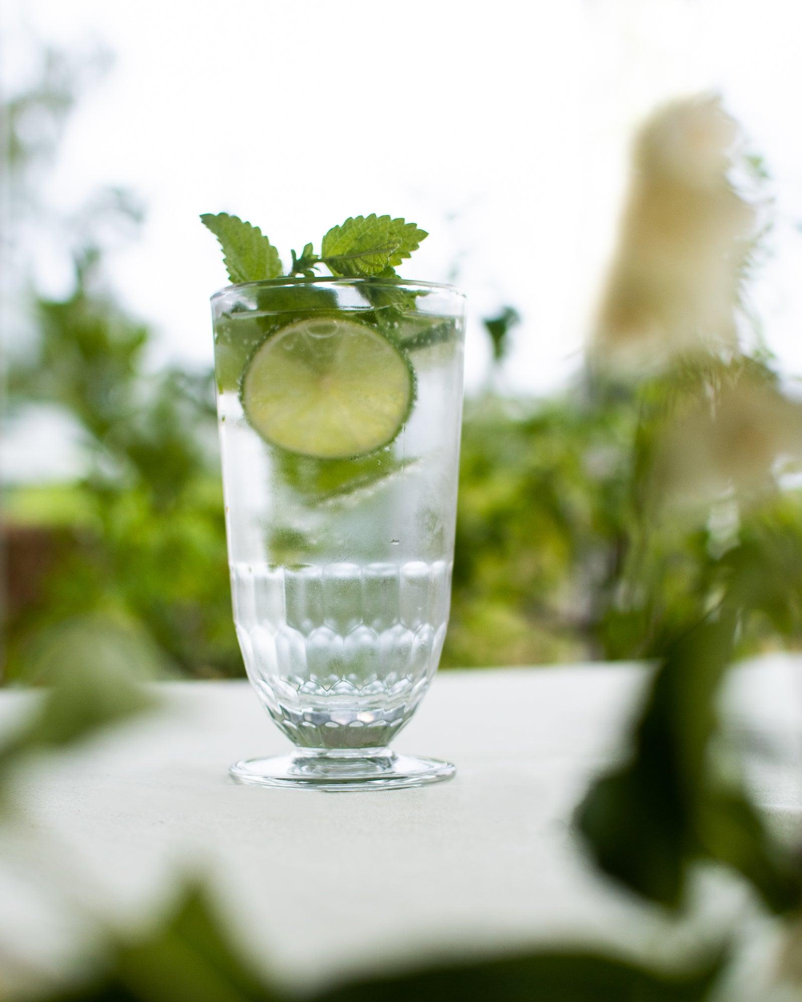 Drinksglas Artois der står udenfor på et bord med en drink i og graniture i toppen