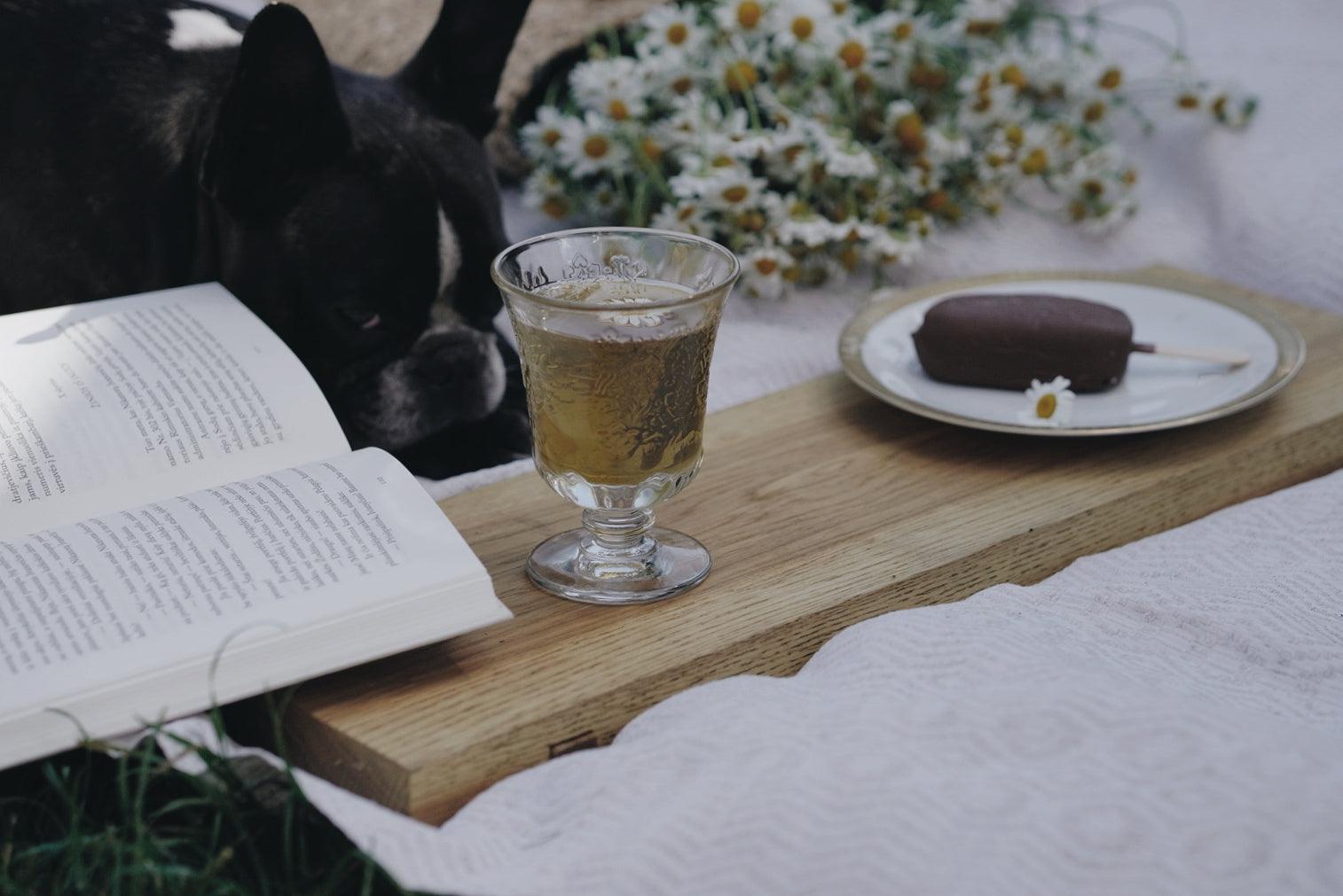 Et lille amboiseglas stående på et træbræt med en is på en tallerken og en sovende hund.